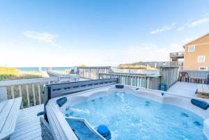 a hot tub on a deck with the ocean in the background at Sea Reunion - Nags Head MP 12.5, Oceanfront, Amazing Views! Pool, Hot Tub, Pets OK in Nags Head +48 photos