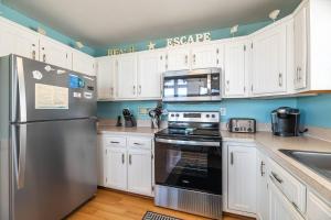 a kitchen with white cabinets and a stainless steel refrigerator at Key to Paradise - Kitty Hawk MP 4, Pool, Hot Tub, Excellent Ocean View, Easy Beach Access in Kitty Hawk