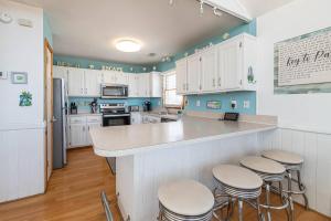 a kitchen with white cabinets and a counter with stools at Key to Paradise - Kitty Hawk MP 4, Pool, Hot Tub, Excellent Ocean View, Easy Beach Access in Kitty Hawk