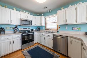 a kitchen with white cabinets and a blue wall at Key to Paradise - Kitty Hawk MP 4, Pool, Hot Tub, Excellent Ocean View, Easy Beach Access in Kitty Hawk