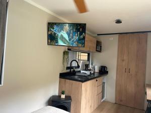 a small kitchen with a sink and a tv on the wall at Tiny Mountain River in Urubamba