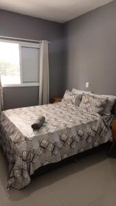 a bedroom with a bed with a comforter and a window at Lar dos Santoprete I in Bertioga +24 photos
