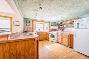 a kitchen with wooden cabinets and a white refrigerator at The Tardis - Kitty Hawk MP 4.5, Ocean View, 275 Yds to Beach, Hot Tub, YR Flex Stays in Kitty Hawk