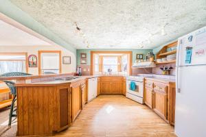 a kitchen with wooden cabinets and a white refrigerator at The Tardis - Kitty Hawk MP 4.5, Ocean View, 275 Yds to Beach, Hot Tub, YR Flex Stays in Kitty Hawk