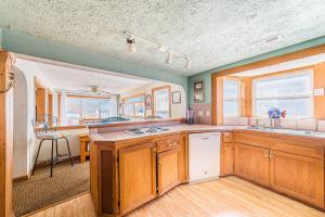 a large kitchen with wooden cabinets and a sink at The Tardis - Kitty Hawk MP 4.5, Ocean View, 275 Yds to Beach, Hot Tub, YR Flex Stays in Kitty Hawk +50 photos