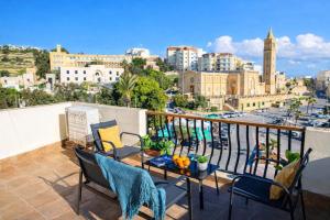 a balcony with chairs and a table with a view of a city at Seafront 4-Bedroom Townhouse with Panoramic Views in Iż-Żlielaq