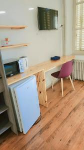 a kitchen with a desk with a refrigerator and a chair at Hôtel 2 Gares in Nevers