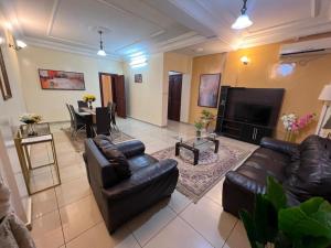 a living room with leather couches and a television at Résidences hôtelières Micheline et Emile BASTOS in Yaoundé