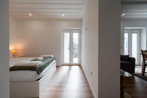 a white bedroom with a bed and a living room at Casa da Chica Apartamento Castelo 1 Esq in Guimarães
