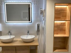 a bathroom with two white sinks and a mirror at Hôtel Angelic in Lourdes