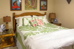 a bedroom with a bed with a green and white comforter at Oceanfront Condo: Stunning Sunrise & Ocean Views in Hauula +30 photos