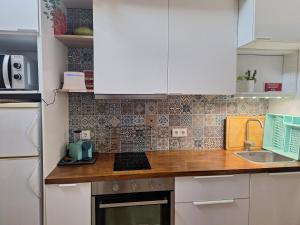 a kitchen with white cabinets and a wooden counter top at Refúgio da Corcha T0 casa de campo e mar Zambujeira do mar in Fataca