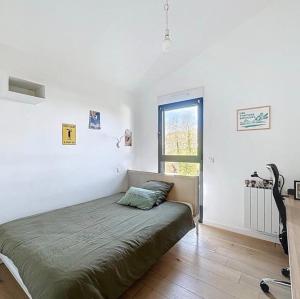 a white bedroom with a bed and a window at La parenthèse basque in BIQ
