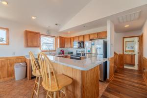 a kitchen with wooden cabinets and a island with bar stools at Carolina Cottage - Kitty Hawk, Oceanside, Walk to Beach, Pool, Hot Tub, Pool Table in Kitty Hawk