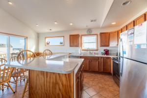 a kitchen with a refrigerator and a table with chairs at Carolina Cottage - Kitty Hawk, Oceanside, Walk to Beach, Pool, Hot Tub, Pool Table in Kitty Hawk