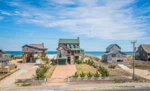 a house on the beach with the ocean in the background at Jockey's Ridge Haven - NH MP 13, Pool-Open Now for 2026, Cabana, Hot Tub, Pets OK, YR Flex Stays in Nags Head