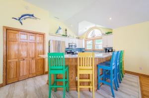 a kitchen with wooden cabinets and blue and yellow chairs at Jockey's Ridge Haven - NH MP 13, Pool-Open Now for 2026, Cabana, Hot Tub, Pets OK, YR Flex Stays in Nags Head +74 photos