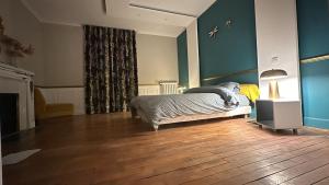 a bedroom with a bed and a lamp on a wooden floor at Chambre dans demeure de caractère in Missy-sur-Aisne +4 photos