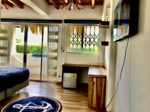 a room with a bed and a tv and windows at Ayampe Sunrise in Ayampe