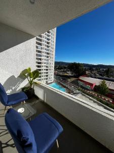 ein Balkon mit zwei Stühlen und Blick auf ein Gebäude in der Unterkunft Depto Parque Víctor lamas in Concepción