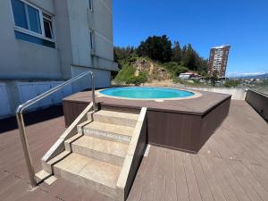 ein Schwimmbad mit Terrasse und Treppe neben einem Gebäude in der Unterkunft Depto Parque Víctor lamas in Concepción