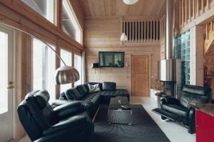 a living room with black leather furniture and a fireplace at Villa Stella in Äkäslompolo