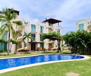a villa with a swimming pool in front of a building at Marina Diamante Plata D5 in Acapulco