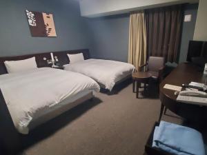 a hotel room with two beds and a desk at Hotel Route-Inn Saga Ekimae in Saga +53 photos