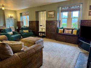 a living room with a couch and chairs and a tv at Hope View House in Castleton