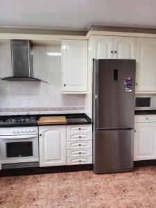 a kitchen with white cabinets and a stainless steel refrigerator at Entre Mar y Montañas in Vall de Uxó