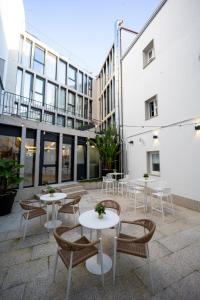 a patio with tables and chairs in front of a building at HOTEL CORONA DE PADRÓN in Padrón