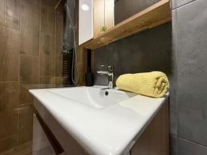 a bathroom sink with a yellow towel sitting on it at Duplex Oasis Rooms in Ada