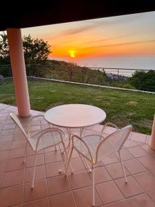 a table and chairs on a patio with the sunset at BLUE APARTMENT in VILLA ANGISI in Drapia
