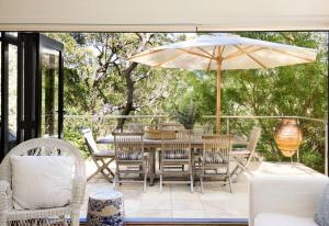 a patio with a table and chairs and an umbrella at Pittwater Hideaway in Palm Beach +25 photos