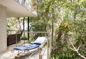 a balcony with a chair on a deck with trees at Pittwater Hideaway in Palm Beach