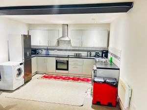 a kitchen with white cabinets and a red appliance at Doncaster 2 Bedroom Luxury Apartment in Doncaster +4 photos
