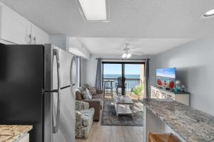 a kitchen with a refrigerator and a living room at Oceanfront 1BR Condo with Corner Balcony Pool in Myrtle Beach