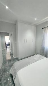 a white bedroom with a large bed and a hallway at B3 bnb House in Ravensmead