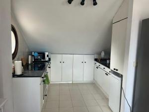a kitchen with white cabinets and a white tile floor at Atico con terraza al mar in Mogro