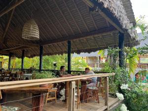 two men sitting at a table under an umbrella at Casa de Campo in Rurrenabaque