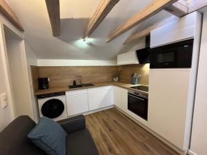 a small kitchen with white cabinets and a black appliance at Melem Apartments 2 in Langen +10 photos