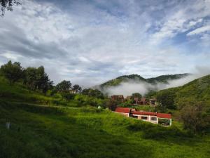 a house on a hill in a green field at Oasis Hotel & Resort Mazamitla in Caliguana