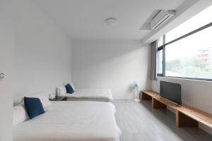 two beds in a room with a tv and a window at Home Rest B&B in Lijia