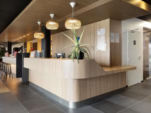 a lobby with a reception counter with a potted plant at ibis Douai Dechy in Dechy