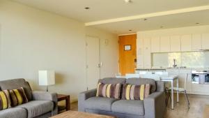a living room with two couches and a kitchen at Resort Apartment 275 in Torquay