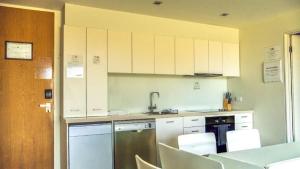 a kitchen with white cabinets and a table and chairs at Resort Apartment 275 in Torquay +7 photos