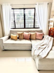 a couch with pillows in a living room with a window at The Eastcape by Akeisha in Bacolod