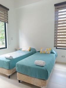two twin beds in a room with windows at Avemaría! in Puente Nacional