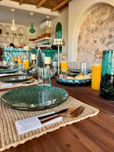 a table with a green plate on a wooden table at La Villa DUCASSE - Piscine, pétanque, calme à Essaouira in Essaouira