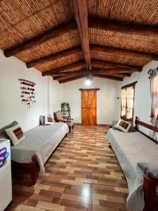 two beds in a room with a wooden ceiling at Casa campo Ayllu in Tilcara